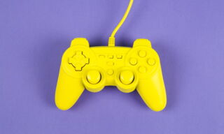 Abstrahierter gelber Gamecontroller vor violettem Hintergrund